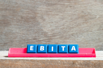 Tile letter on red rack in word EBITA (abbreviation of  earnings before interest, taxes and amortization) on wood background