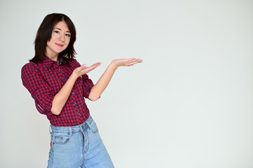 Portrait of a pretty asian brunette girl with black hair in a burgundy shirt and blue jeans on a white background. It stands right in front of the camera, with emotions in various poses.