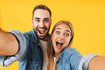 Fototapeta premium Image of amazed couple screaming at camera while taking selfie photo