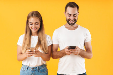 Image of positive couple азsmiling while using smartphones together