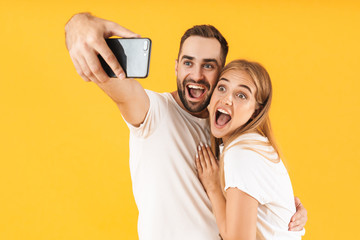 Image of young couple smiling while taking selfie photo on cellphone