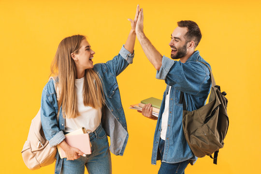 Image of cheerful students smiling while holding exercise books