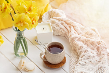 Fototapeta na wymiar Spring still life with yellow flowers, tea and candle,