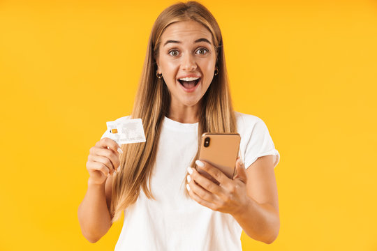 Image of pleased woman smiling while holding smartphone and credit card