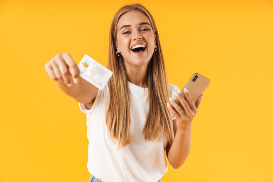 Image of young woman smiling while holding smartphone and credit card