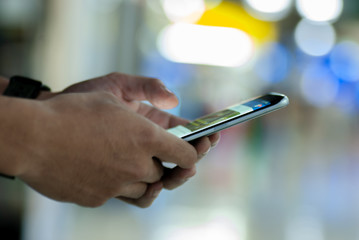Man's hand using smart phone in interior.