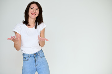 Portrait of a pretty asian brunette girl with black hair in a white t-shirt and blue jeans on a white background. It stands right in front of the camera, with emotions in various poses.