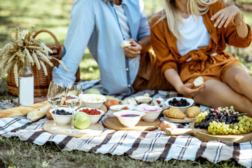 Couple having romantic breakfast outdoors, close-up view on the picnic blanket with lots of tasty food