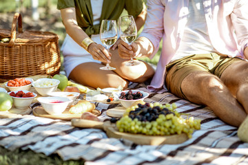 Couple having romantic breakfast outdoors, close-up view on the picnic blanket with lots of tasty food - obrazy, fototapety, plakaty