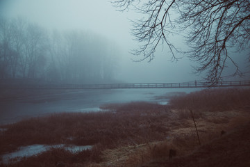 Obraz premium Lonely man in mist on .old wooden bridge. Foggy image.