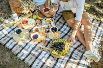 Couple having romantic breakfast outdoors, close-up view on the picnic blanket with lots of tasty...