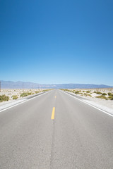 View of a vast Death Valley landscape, empty roads , rock formations and the badwater basin salt deposits.