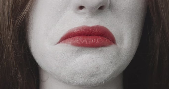 She is pulling down the corners of her mouth - close-up of a teenage girl, who is made-up for Halloween or a costume party. Rehearsing different facial expressions, she is making a pout - ProRes