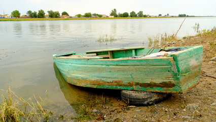 Naklejka na ściany i meble Old wooden fishing boat by the river in a Russian village