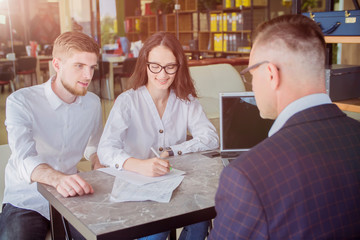 Couple meeting with financial advisor. Businessman with customers signing contract