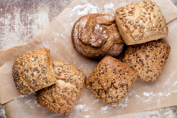Gold rustic crusty loaves of bread and buns on wooden background. Still life captured from above top view, flat lay.