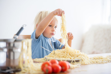 Little baby boy, toddler child, eating spaghetti for lunch and making a mess at home