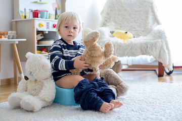 Cute toddler boy, potty training, playing with his teddy bear