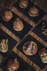 A close up shot of a selection of canape dishes. Concept of catering, hospitality and lifestyle. Small snacks and nibbles served on black slates for a private reception.