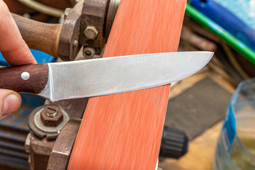 sharpening polishing kitchen knife blade on the belt grinder sander equipment. Knife making.