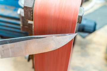 Grinding polishing sharpening knife blade on the belt grinder sander equipment. Knife making.