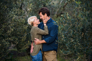 Young affectionate couple standing outdoors in olive orchard, hugging.