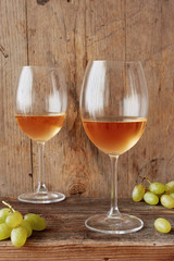 Two glasses of orange wine with white grapes over wooden background. Close up.