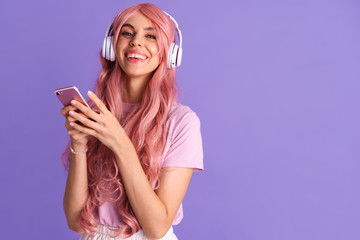 Positive young girl listening music with headphones using mobile phone.