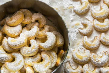 Home baked German Austrian traditional Christmas cookies vanilla crescents in tin box and on tray powdered with castor sugar. Holiday baking with kids sweet treats