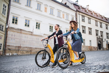 Young tourist couple travellers with electric scooters in small town.