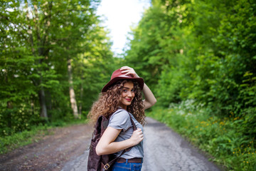 Young tourist woman traveller with backpack walking in nature.