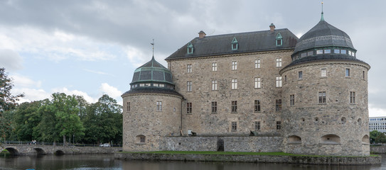Fototapeta premium Orebro castle with clouds. Castle view from the pond side. Travel photo. Background or illustration.