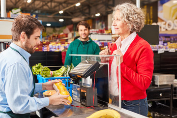 Kundin an der Supermarkt Kasse schaut auf Kassierer