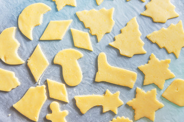Rolled out shortbread dough with cut out Christmas cookies of various shapes on parchment paper top view. copy space. Holiday baking with kids concept. Cozy atmosphere