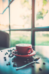 Red coffee cup decorated with coffee beans on the table with copy space.