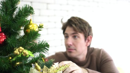 Caucasian man excited decorating Christmas tree and waiting to surprise family