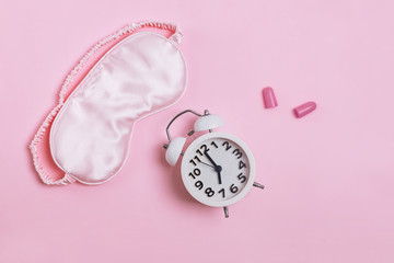 Sleeping mask, alarm clock and earplugs pn patel pink background,