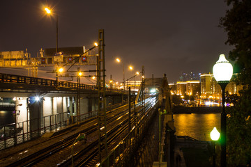 urban view of the railway via the metal bridge next to the freeway in the background of the night sky in Moscow Russia