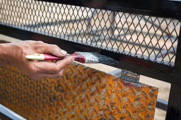 Workers use black steel paint brushes.