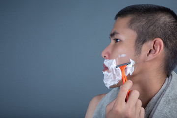 Shaving handsome guy shaved on the face on a gray background.