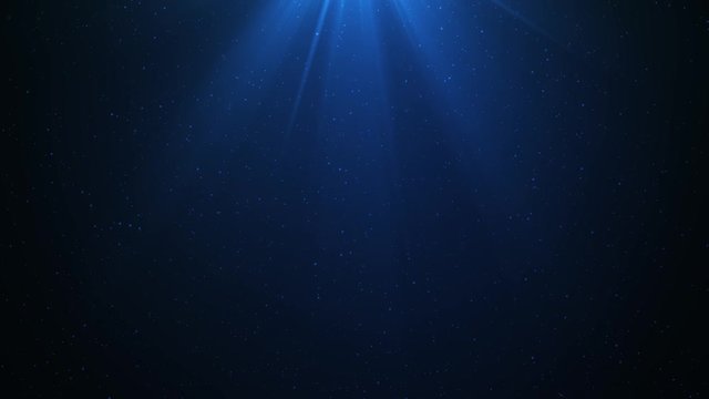 Computer generated footage of particles moving around while light flares from above. Footage creates the illusion of light passing through deep ocean water.