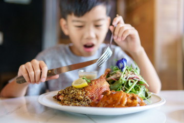 Young boy eat pork steak