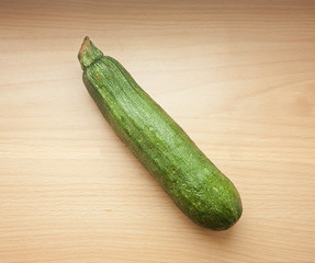 A green courgette or zucchini on a wooden table
