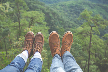 Couples raise their feet pointing to the hillside in tropical forests, hiking, traveling, climbing.