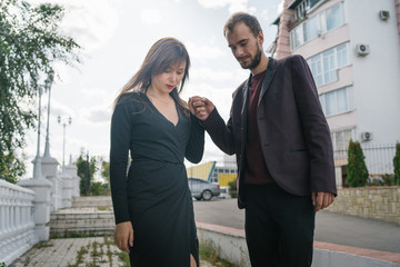 Happy pair. Walking In The City. Young couple walks holding woman in a long dress. Beautiful stylish pair of European looks A couple walks through the streets of the city.