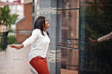 Formally dressed african american business woman in white blouse and red trousers. Successful dark...