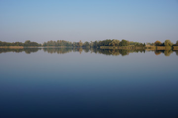 Autumnally discolored trees reflecting in the calm waters of the lake on an autumn afternoon in a small Polish town Lipiany in the West Pomeranian