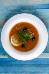 soup with meat and vegetables in a white plate on a wooden background Russian cuisine