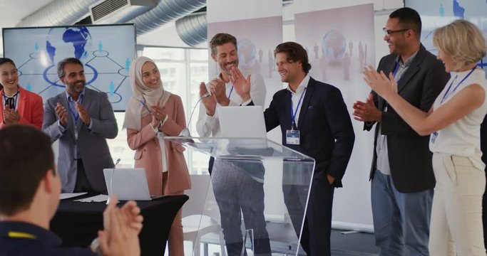 Male speaker and applauding audience and colleagues at a business presentation