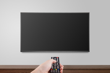 Television on white wall with hand using remote control, TV 4K flat screen lcd or oled, plasma...